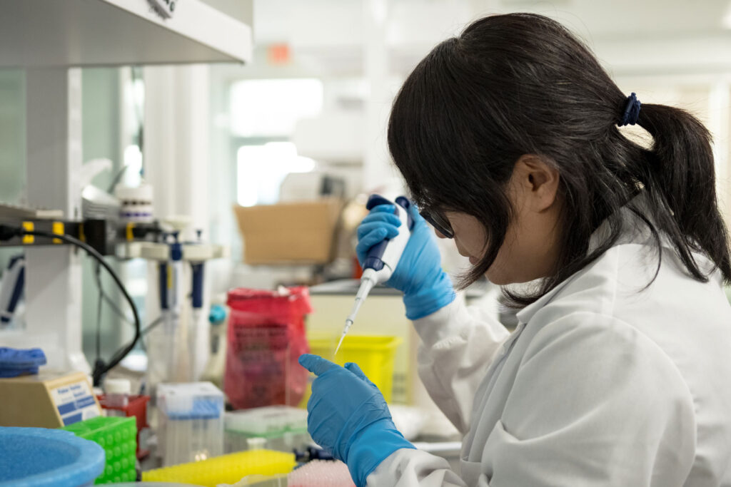 Cirsium Biosciences scientist holding pipette in lab with lab coat on